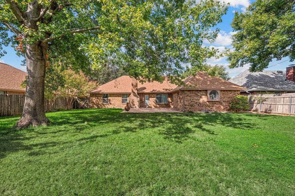 339 Park North Lane, Keller, TX 76248 Spacious backyard featuring a brick exterior, mature trees, wood privacy fencing, and a stone patio