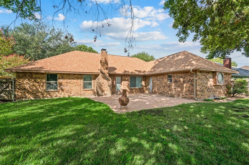 339 Park North Lane, Keller, TX 76248 Brick exterior featuring a masonry chimney, expansive paved patio, and mature trees