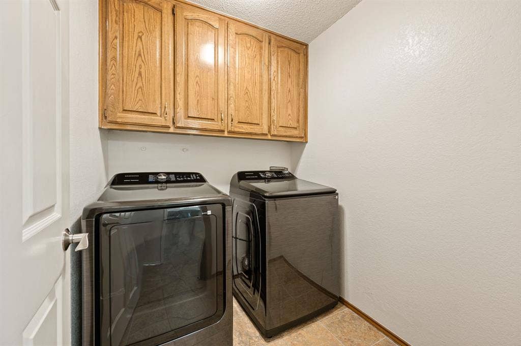339 Park North Lane, Keller, TX 76248 Laundry area featuring built-in wood-finish cabinetry, neutral wall surfaces, and tile flooring