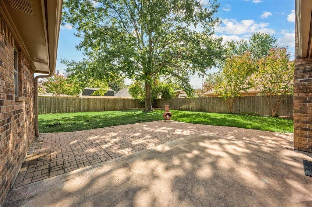 339 Park North Lane, Keller, TX 76248 Rear exterior patio featuring brick pavers, concrete slab, brick masonry siding, wood privacy fencing, and mature trees