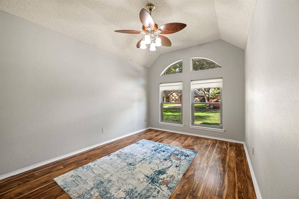 339 Park North Lane, Keller, TX 76248 Bedoom featuring vaulted ceilings, wood-finish flooring, dual windows topped with arched clerestory windows, and a multi-light ceiling fan