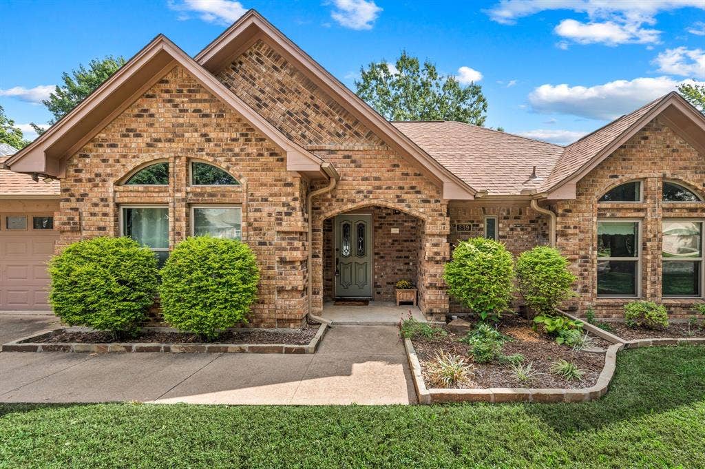 339 Park North Lane, Keller, TX 76248 Multi-gabled brick exterior featuring arched windows, a recessed covered entryway, and stone-bordered landscaping beds