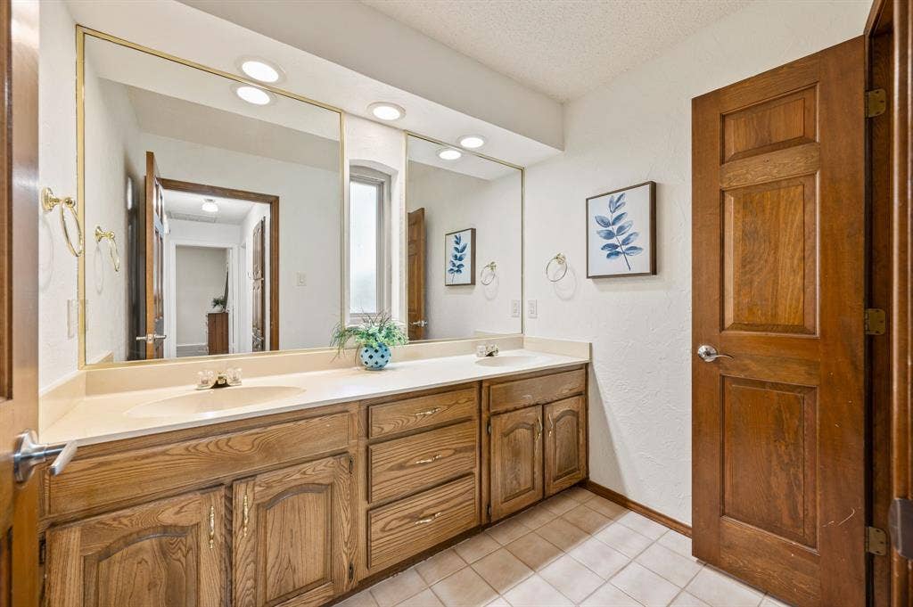 339 Park North Lane, Keller, TX 76248 Dual-sink vanity with wood-finish cabinetry, solid-surface countertop, recessed ceiling lighting, and full-width wall mirror