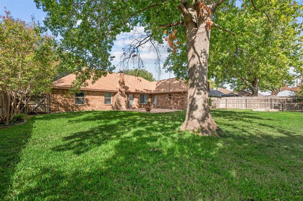 339 Park North Lane, Keller, TX 76248 Expansive backyard featuring a brick exterior, stone-paved patio, mature trees, and a wood privacy fence