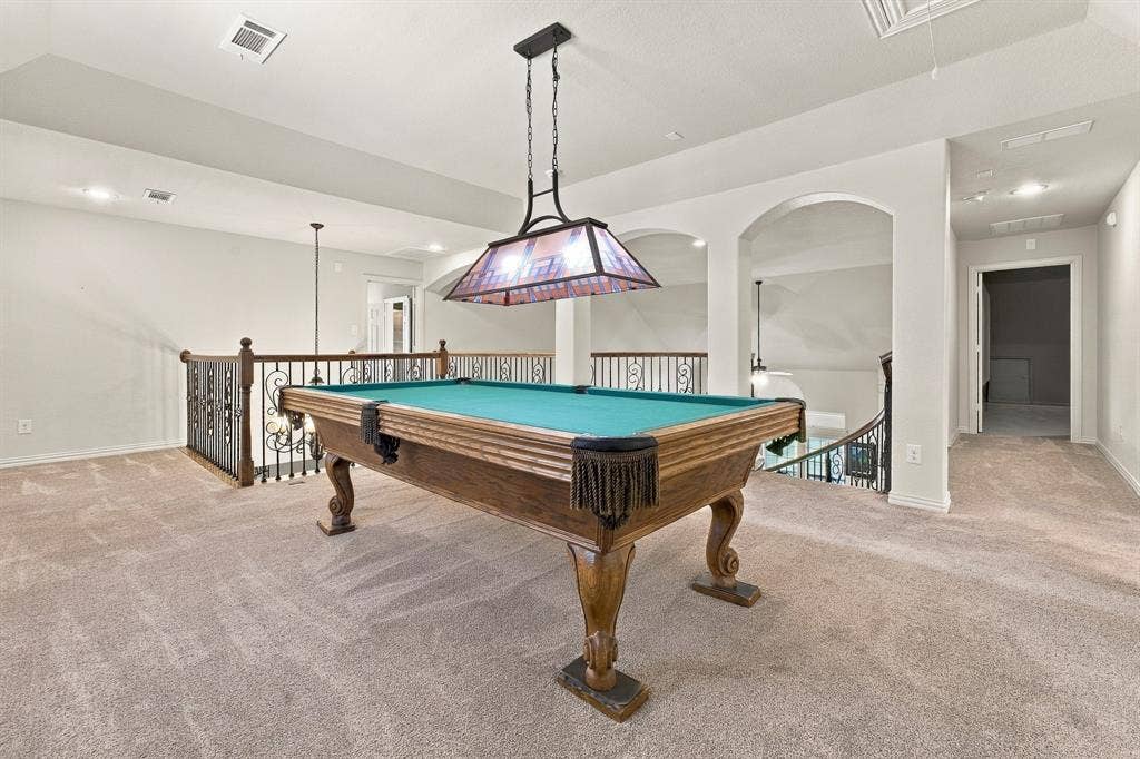 Open floor plan featuring arched architectural pass-throughs, custom wrought-iron railings, tray ceilings, and recessed lighting
