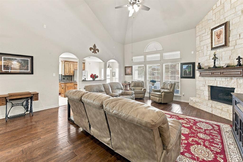 Living area featuring a vaulted ceiling, floor-to-ceiling masonry fireplace, wood-finish flooring, and arched architectural openings