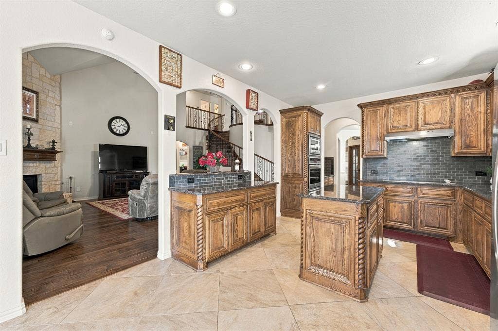 Kitchen featuring stained wood cabinetry with rope detailing, tiled backsplash, center island, recessed lighting, and tile flooring
