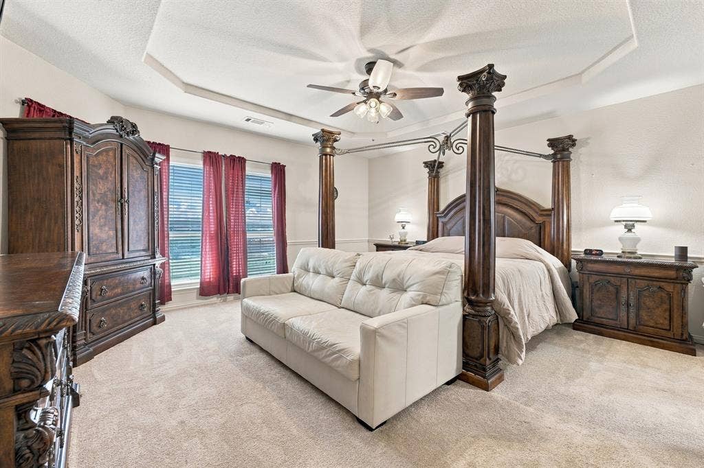 Room featuring an octagonal tray ceiling, neutral wall-to-wall carpeting, and a ceiling fan with integrated lighting