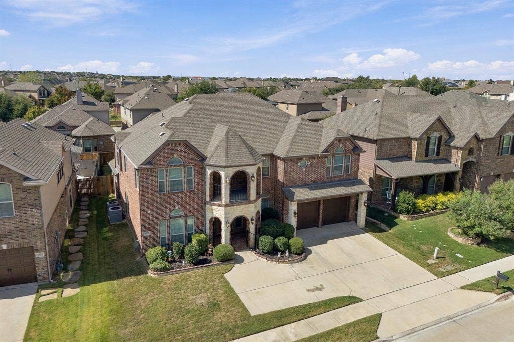 Multi-story brick and stone veneer exterior featuring dual stacked covered porches, a hipped roofline, and an attached two-car garage