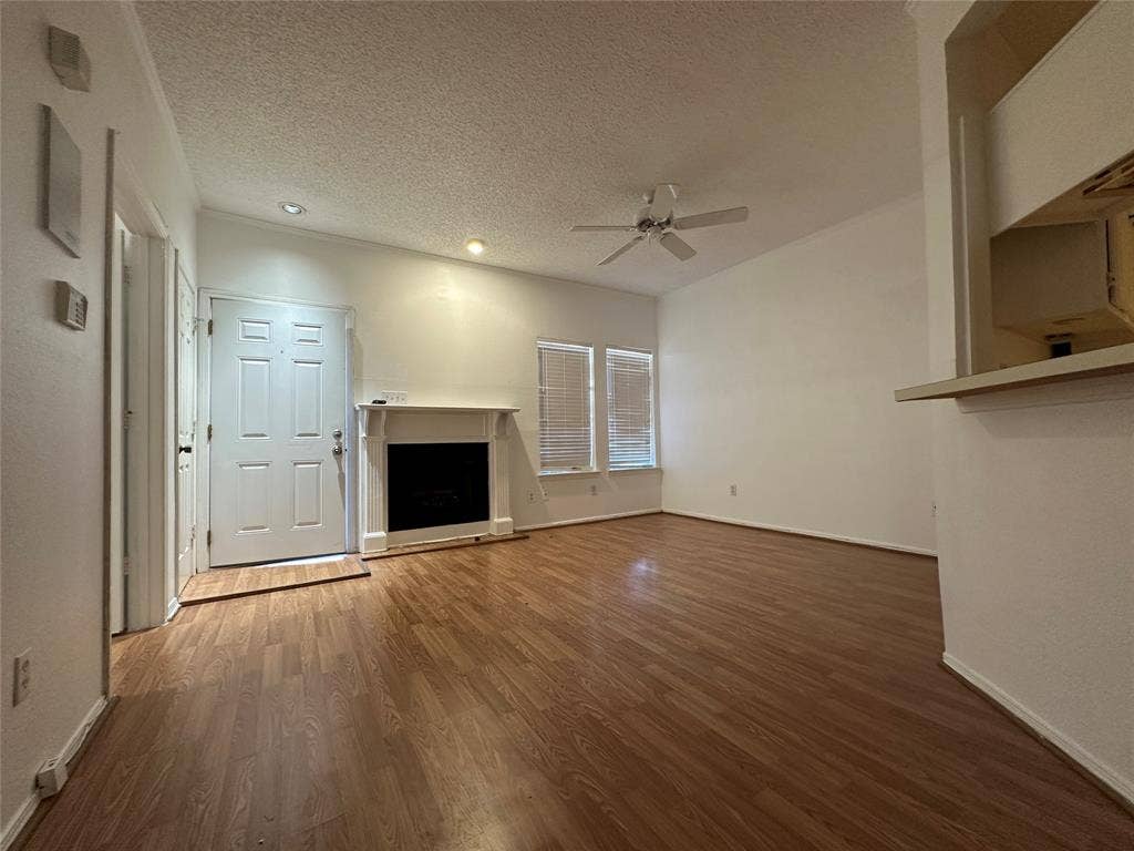 5757 E University Boulevard, #27p, Dallas, TX 75206 Interior space featuring wood-finish flooring, a fireplace with a decorative mantel, recessed lighting, a ceiling fan, and dual windows