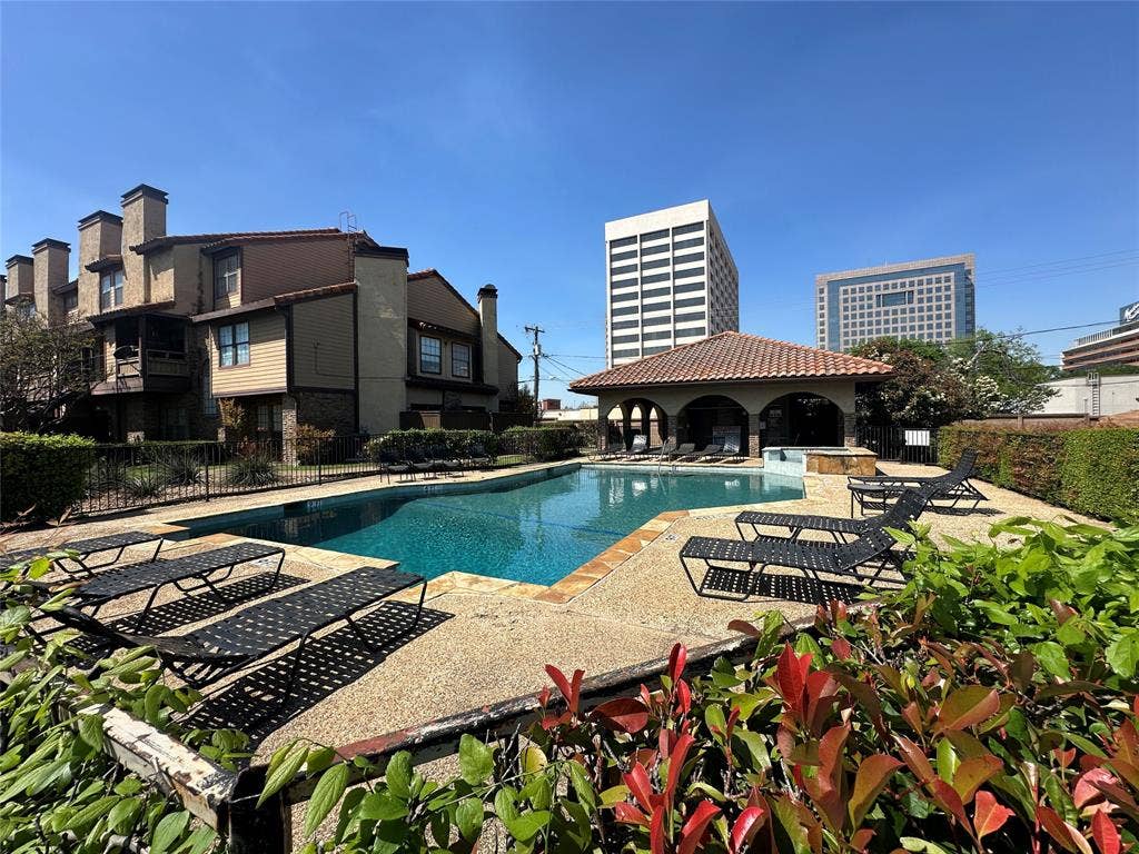 5757 E University Boulevard, #27p, Dallas, TX 75206 In-ground swimming pool with a stone deck, enclosed by perimeter fencing and accompanied by a covered pavilion with a tile roof