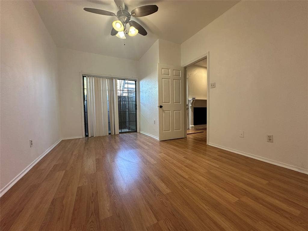 5757 E University Boulevard, #27p, Dallas, TX 75206 Wood-finish flooring, ceiling fan with integrated lighting, and sliding glass doors with vertical blinds