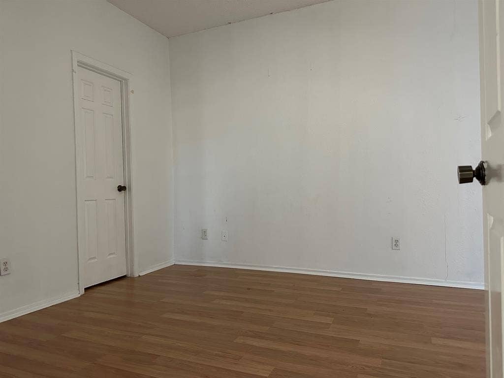 5757 E University Boulevard, #27p, Dallas, TX 75206 Neutral-toned room featuring wood-finish flooring and a single-panel interior door with a metallic knob