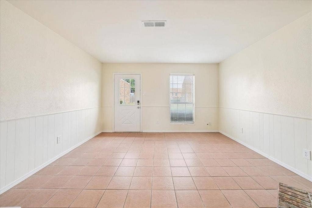 703 Lee Street, #6, Mesquite, TX 75149 Interior room featuring light-toned ceramic tile flooring, horizontal wall wainscoting, a neutral color palette, and a glass-paneled exterior door
