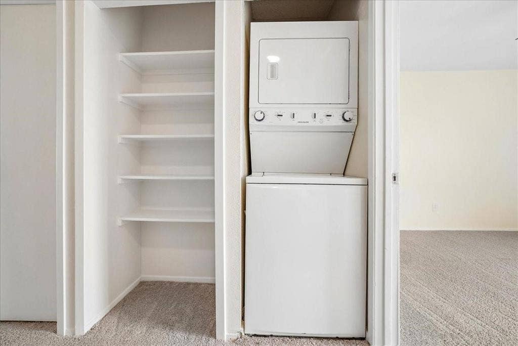 703 Lee Street, #6, Mesquite, TX 75149 Laundry alcove featuring a stacked white washer and dryer unit with built-in storage shelving