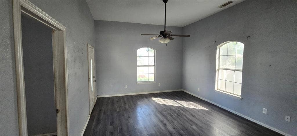 517 Clark Street, Garland, TX 75040 High ceilings featuring a central ceiling fan, two arched windows with grid detailing, and wood-finish flooring