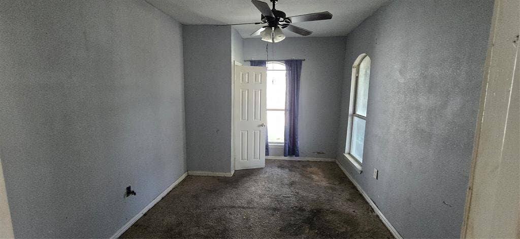 517 Clark Street, Garland, TX 75040 Room featuring carpeting, a ceiling fan with integrated lighting, a multi-panel interior door, and an arched window