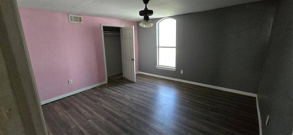 517 Clark Street, Garland, TX 75040 Room featuring wood-finish flooring, an arched window, and a built-in closet with a six-panel door