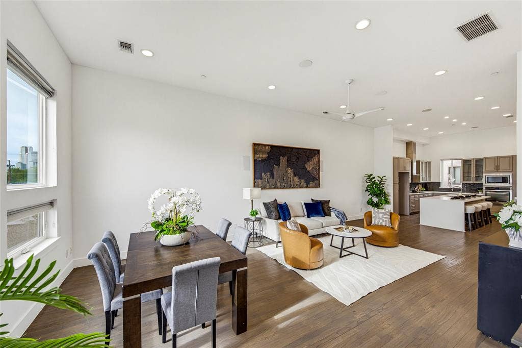 Open-concept living space featuring wood-finish flooring, recessed lighting, ceiling fan, and large windows with integrated blinds