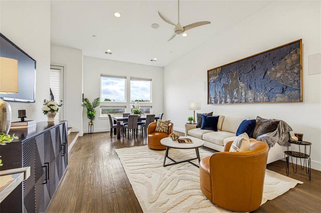 Living area featuring wood-finish flooring, high ceilings, recessed lighting, a modern ceiling fan, and large windows