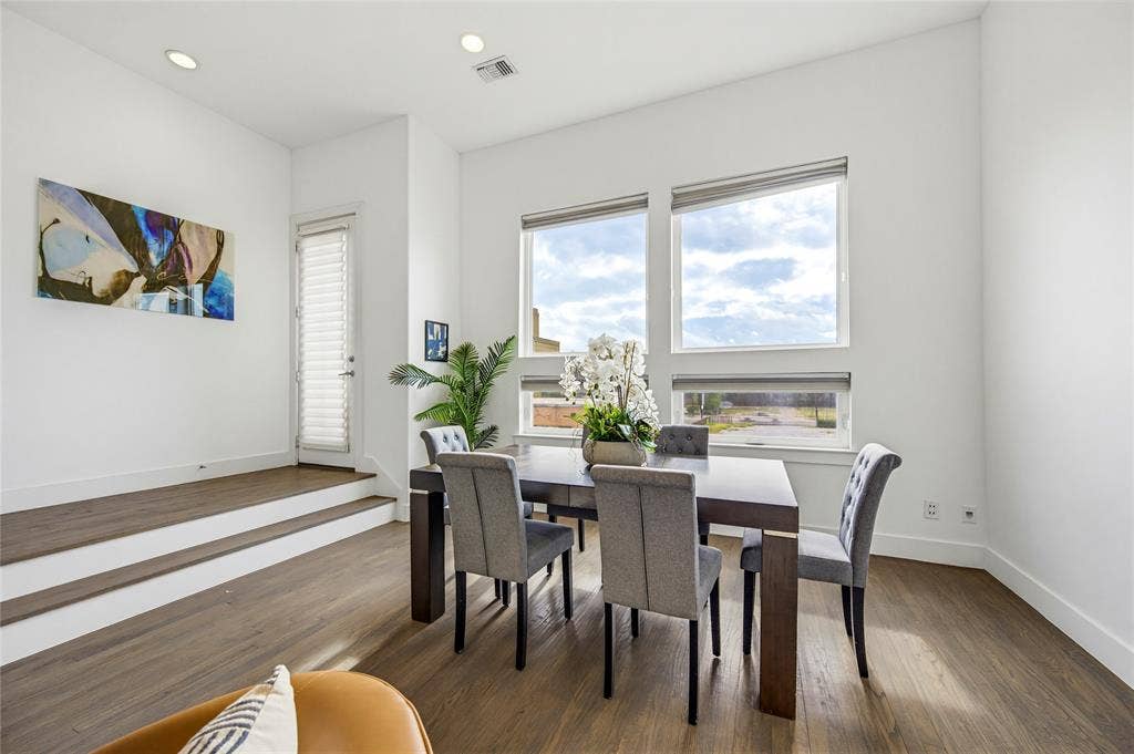 High ceilings with recessed lighting, large picture windows, elevated step-up landing, and wood-finish flooring