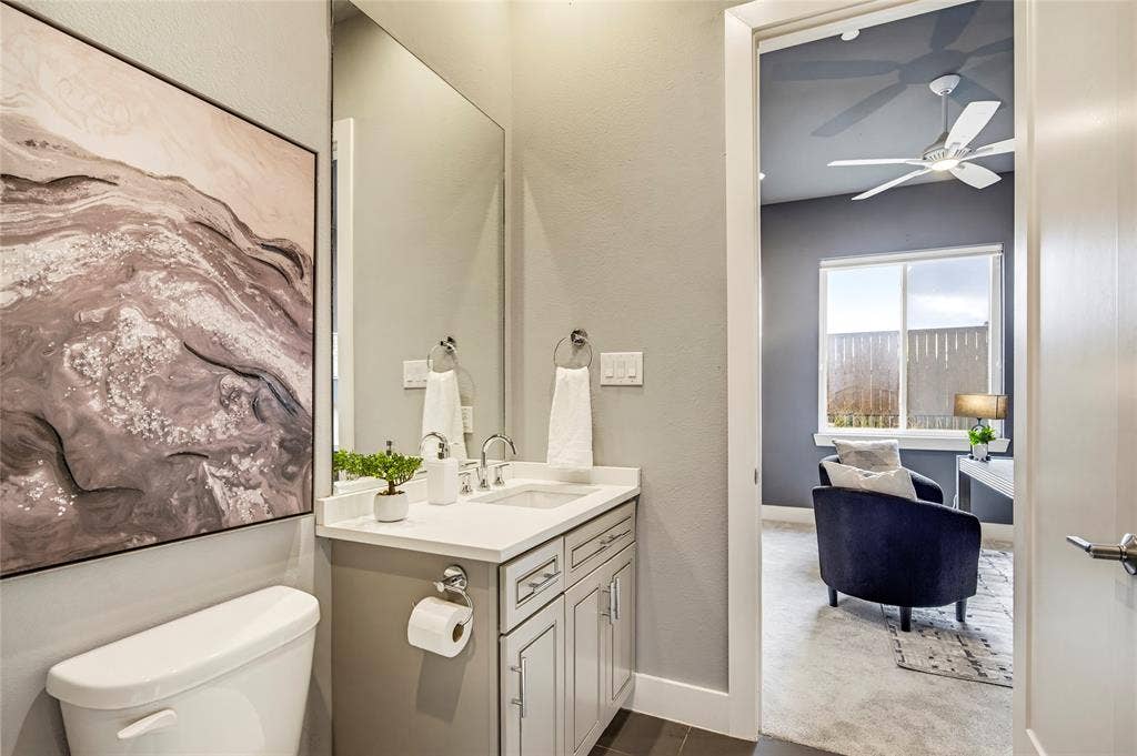 Bathroom featuring a vanity with white countertop, undermount sink, dual-handle faucet, and grey cabinetry, complemented by a large wall-mounted mirror