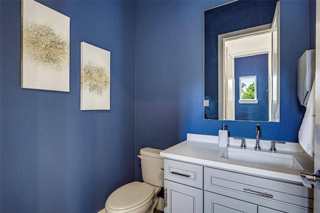 Shaker-style vanity with a solid-surface countertop, integrated basin, chrome-finish faucet, and large wall-mounted mirror