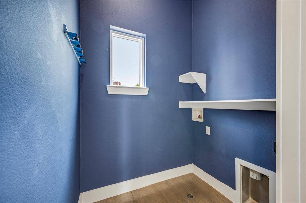 Utility space featuring wood-finish flooring, a single window, white built-in shelving, and dedicated hookups