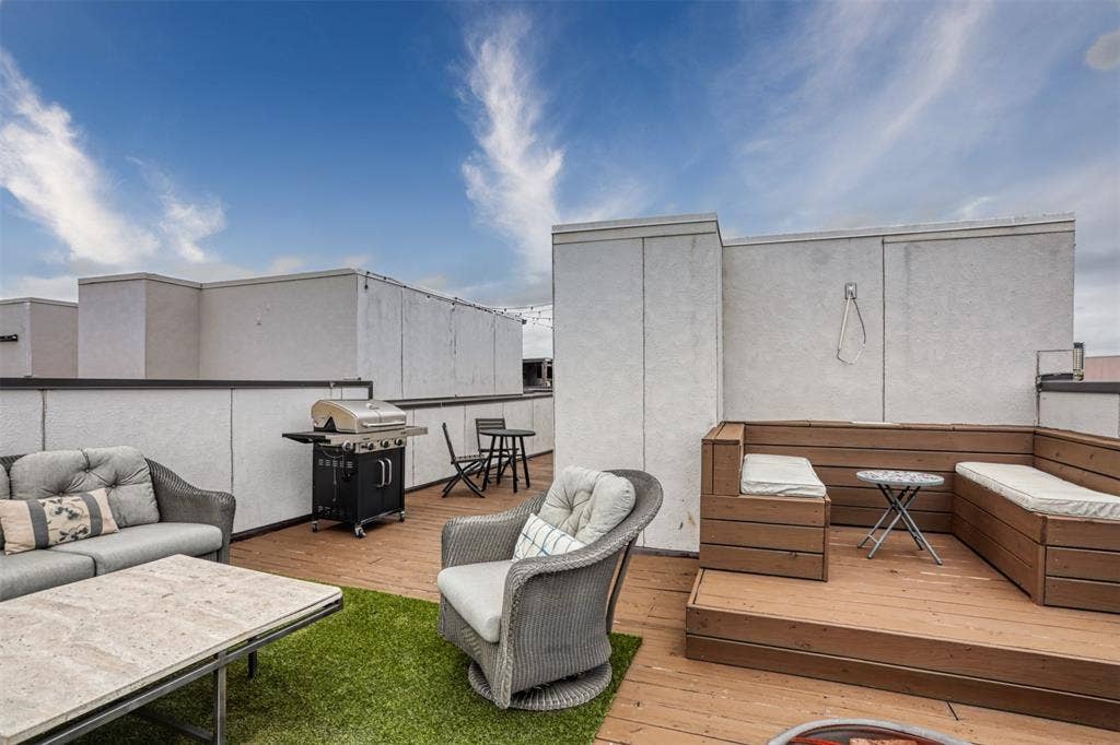 Rooftop terrace featuring wood-finish decking, built-in wooden bench seating, synthetic turf inlay, and high parapet walls