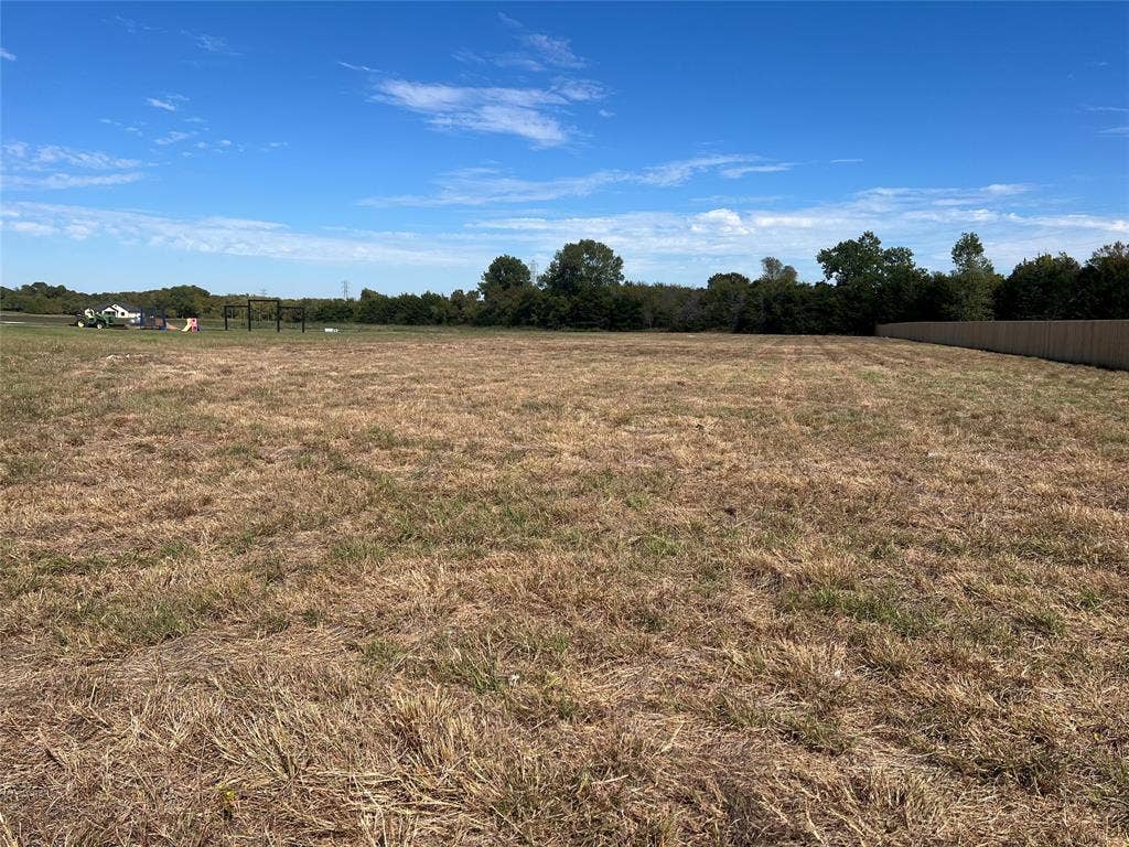 Expansive parcel of land featuring level terrain and perimeter wood fencing