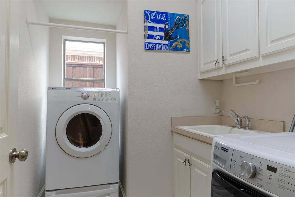 Laundry room featuring white cabinetry, a built-in utility sink with a faucet, and a wall-mounted hanging rod