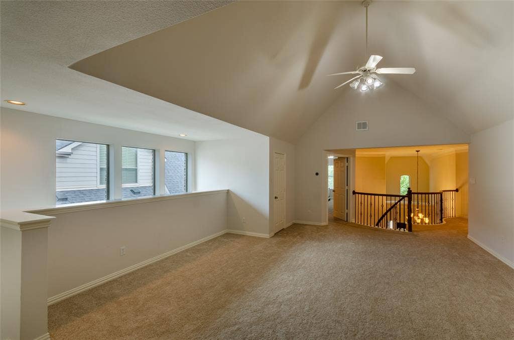 Game room Vaulted ceiling, ceiling fan with integrated lighting, recessed lighting, and wooden staircase railing