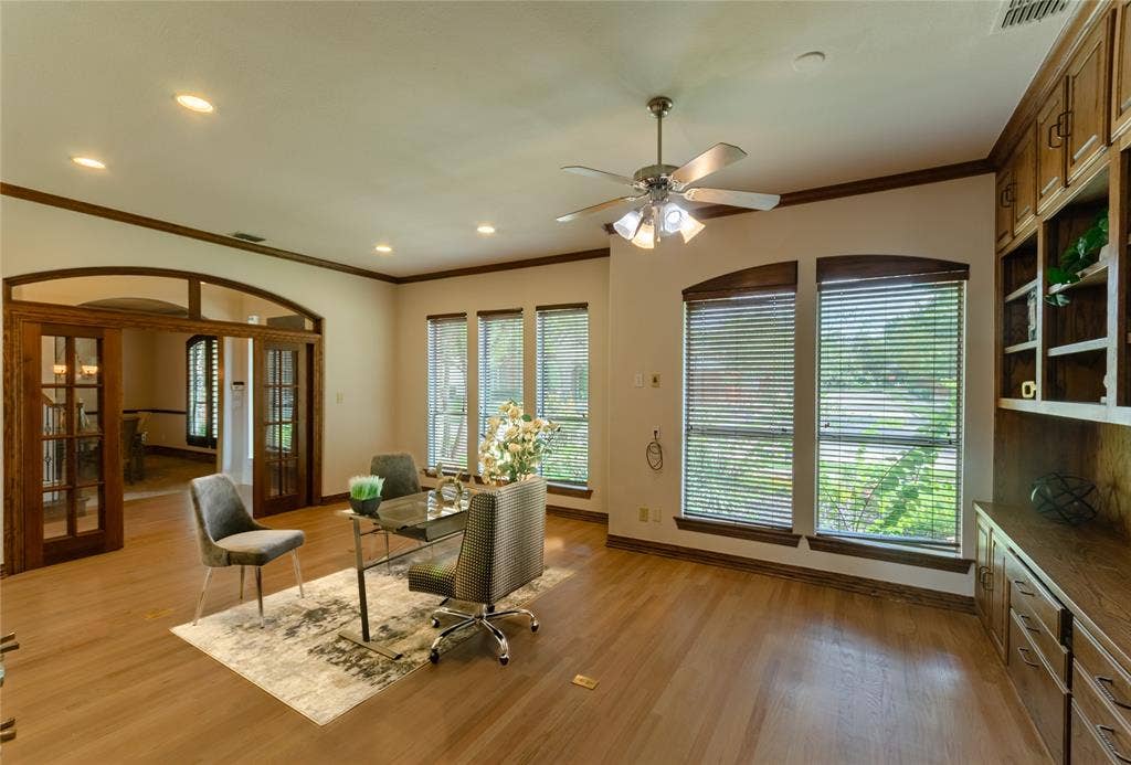 Wood-finish flooring, custom built-in cabinetry, arched wood-framed glass paneled doors, and recessed lighting
