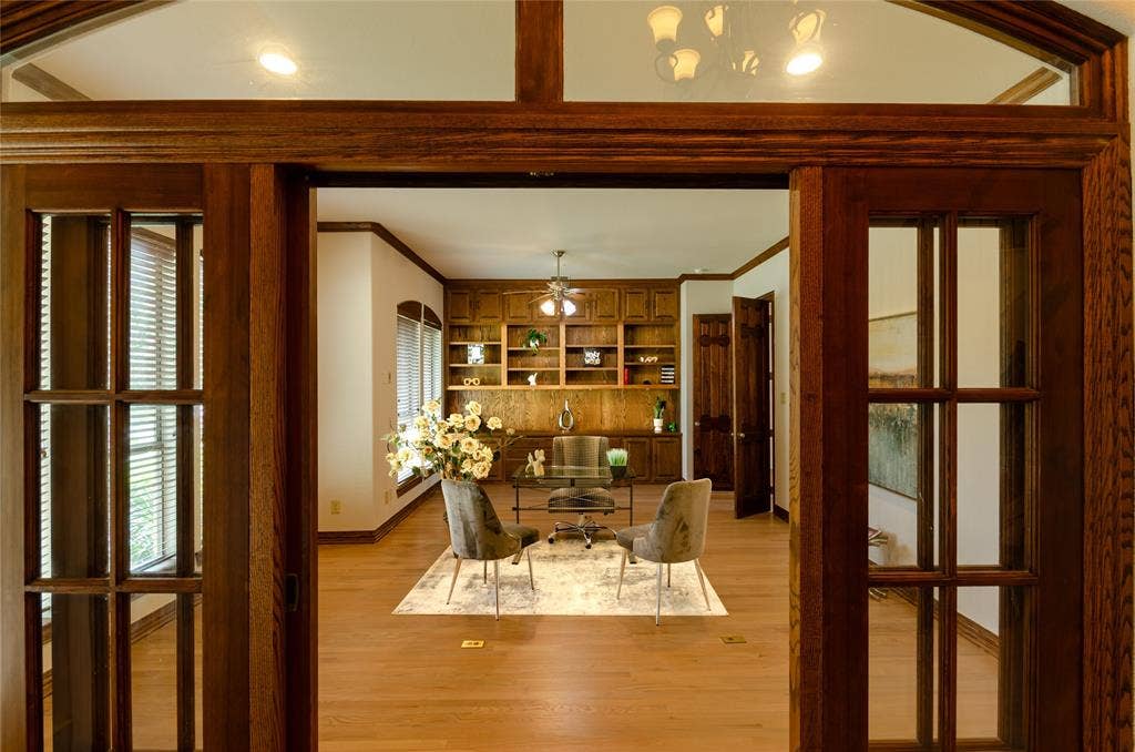 Stained wood French doors with transom windows, wood-finish flooring, and expansive wall-to-wall built-in wood cabinetry