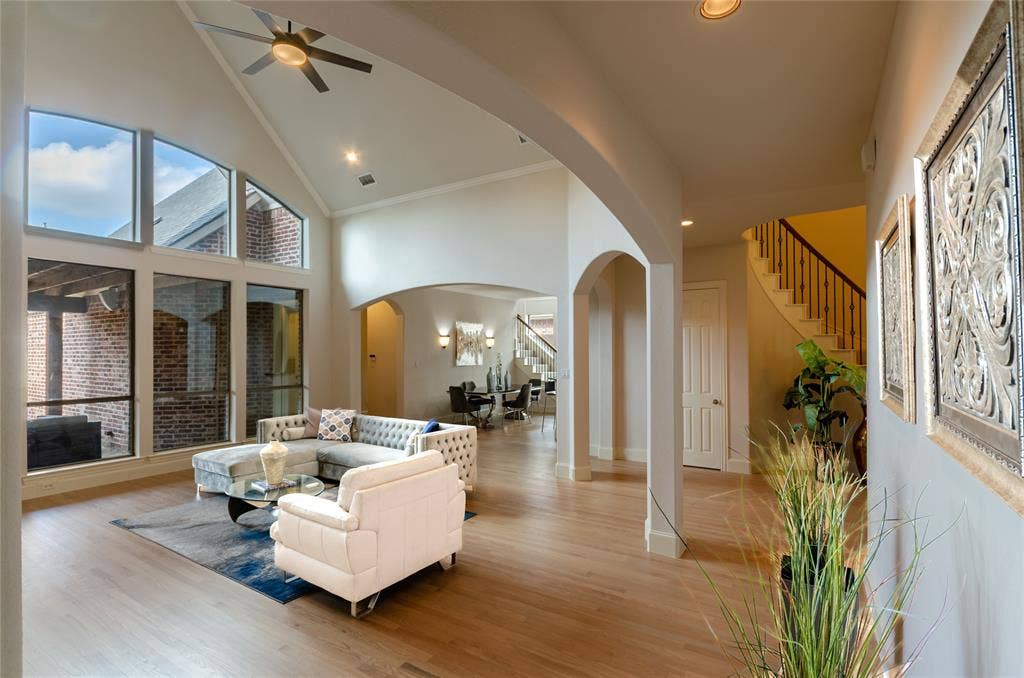 Vaulted ceilings featuring a recessed ceiling fan, expansive floor-to-ceiling windows, wide-plank wood-finish flooring, and arched architectural entryways