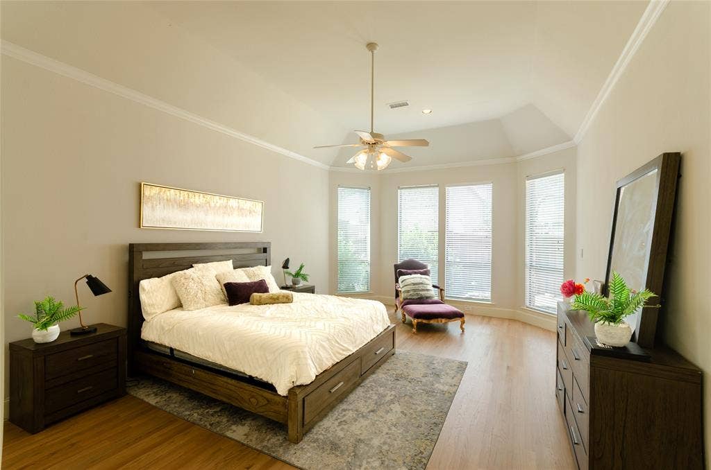 Vaulted ceilings with crown molding, wood-finish flooring, and multiple windows with horizontal blinds
