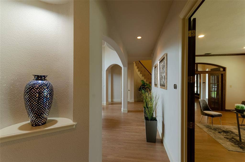 Interior architecture featuring recessed wall niches, arched entryways, wood-finish flooring, and recessed ceiling lighting