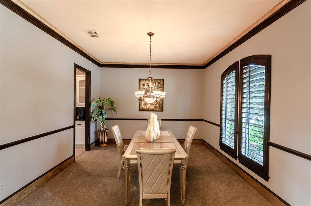 Formal room featuring dark wood crown molding, chair rail trim, and window casings