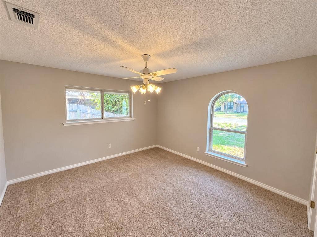 3408 Bellah Court, Irving, TX 75062 Neutral-toned interior featuring wall-to-wall carpeting, a multi-light ceiling fan, a rectangular window, and an arched window