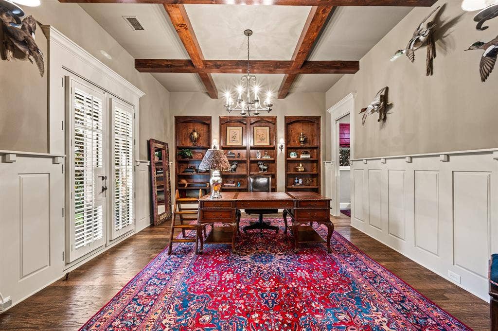 This beautifully appointed study features rich built-in wood shelving and a cleverly concealed desk tucked behind a pocket door, offering a sophisticated and functional workspace.