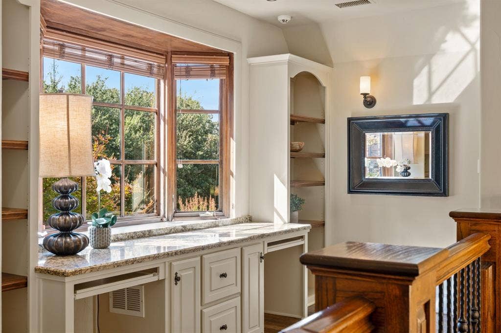 At the top of the stair landing, beautiful built-in shelving and a thoughtfully designed desk area create an inviting workspace bathed in abundant natural light.