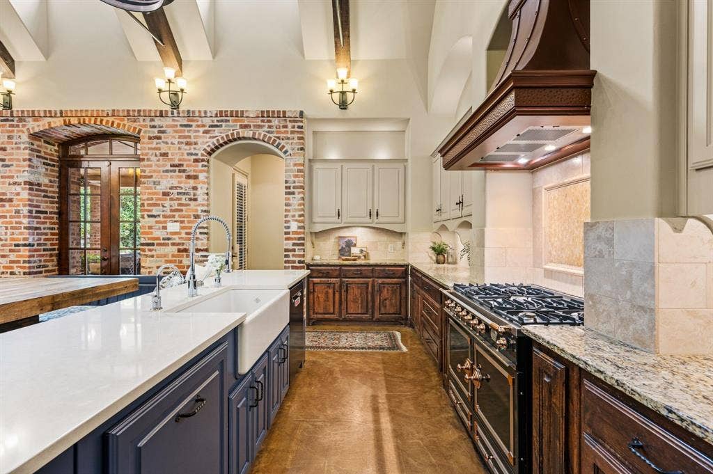 A stunning copper vent hood takes center stage above the exquisite La Cornue range, while abundant cabinetry provides exceptional storage, blending timeless elegance with everyday functionality.