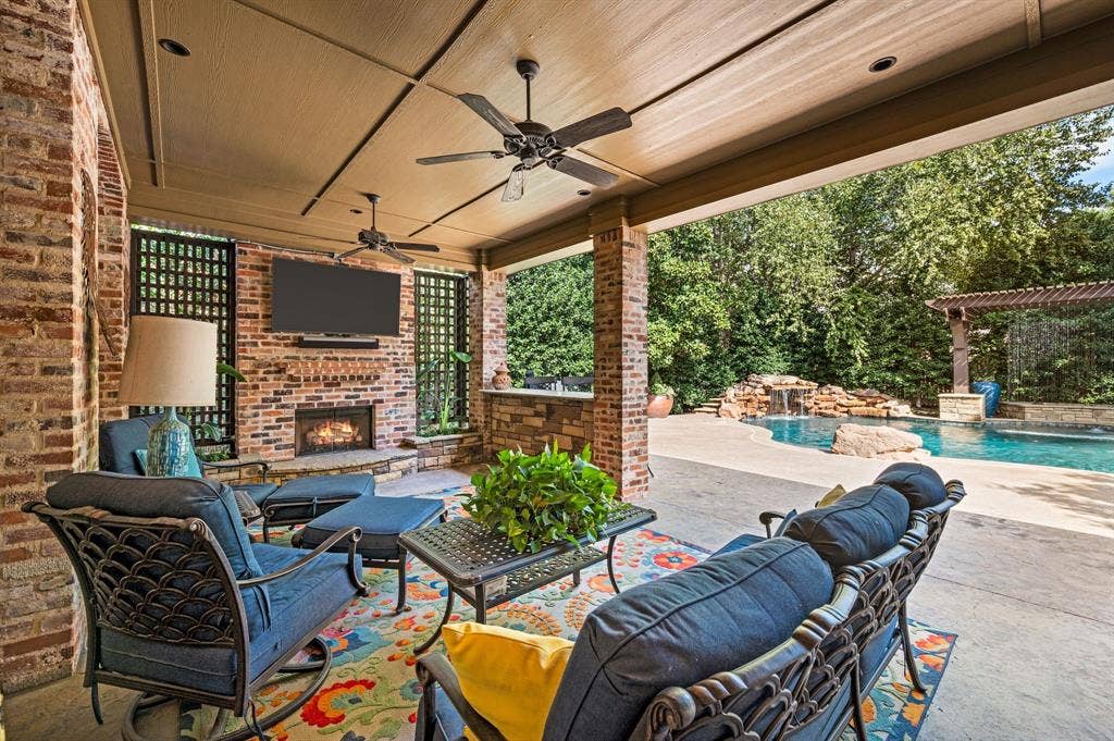 The inviting covered patio creates the perfect outdoor retreat, featuring a built-in grill, bar, and cozy fireplace.