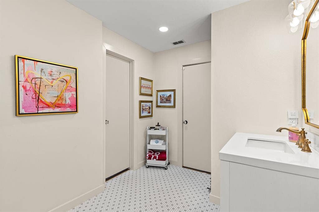 2425 S 2nd Street, Waco, TX 76706 Bathroom featuring a white vanity cabinet, rectangular under-mount sink, brass finish widespread faucet, and geometric-patterned tile flooring