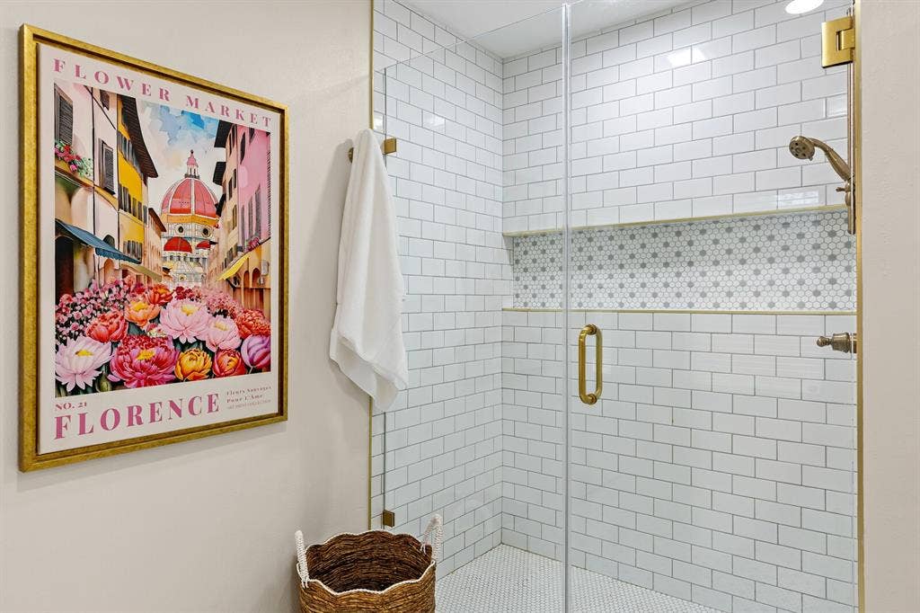 2425 S 2nd Street, Waco, TX 76706 Walk-in shower featuring white subway wall tile, a geometric-patterned tile niche, brass-finish hardware, and a frameless glass door