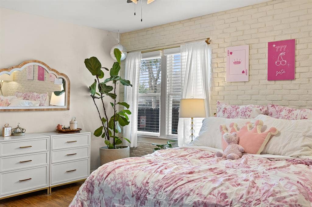 2425 S 2nd Street, Waco, TX 76706 Interior space featuring a painted brick accent wall, double-hung windows with horizontal blinds, and wood-finish flooring