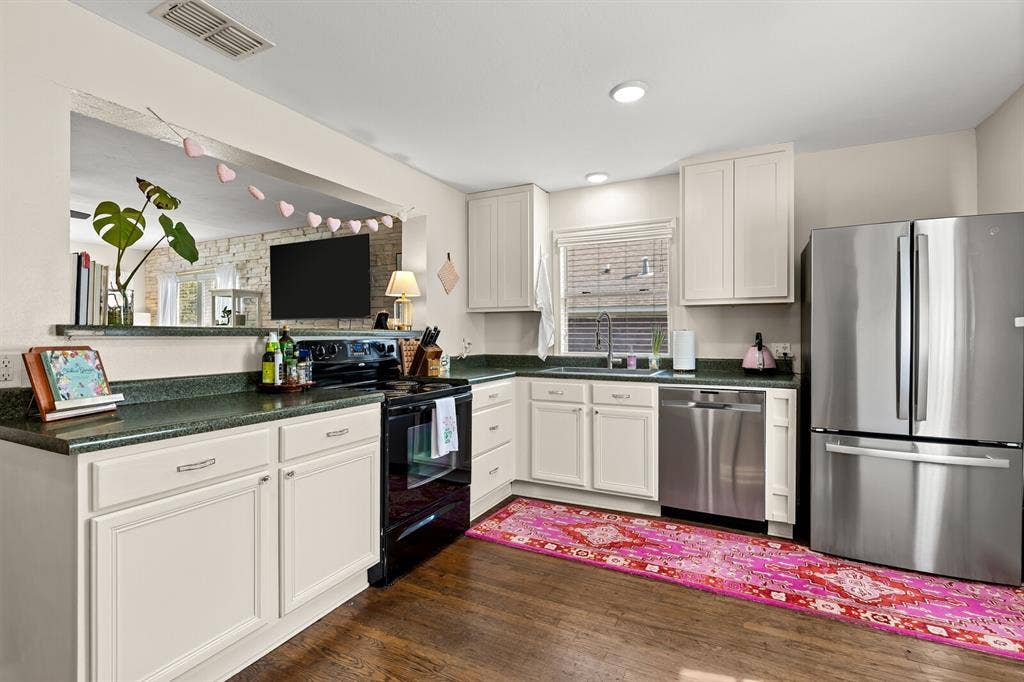 2425 S 2nd Street, Waco, TX 76706 Kitchen featuring white cabinetry, solid-surface countertops, recessed lighting, and stainless steel appliances, including a refrigerator and dishwasher, set against wood-finish flooring