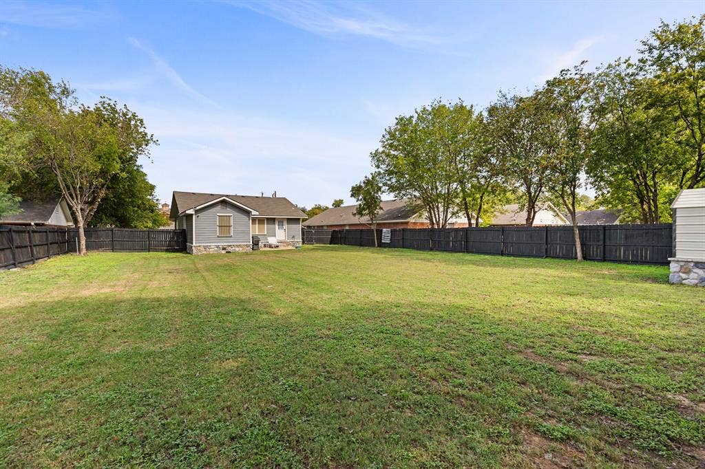 2425 S 2nd Street, Waco, TX 76706 Expansive backyard featuring a large grass lawn, a solid black wood-style privacy fence, and mature trees