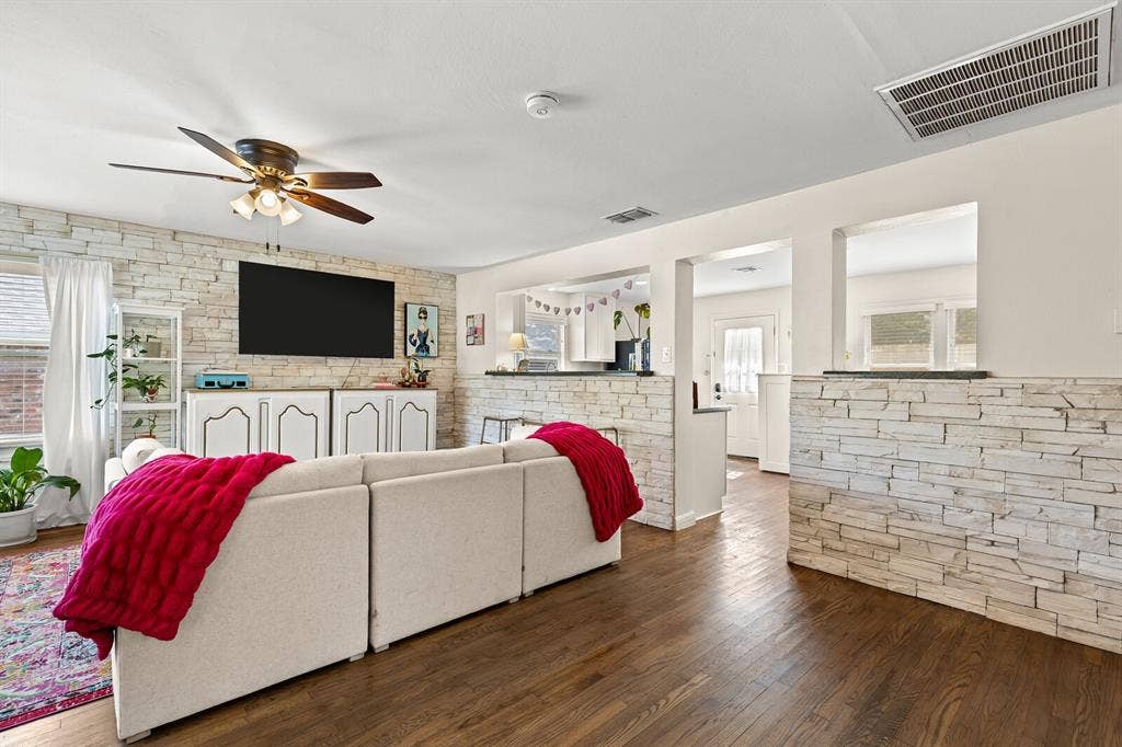 2425 S 2nd Street, Waco, TX 76706 Living area featuring stack-stone accent walls, wood-finish flooring, and a ceiling fan with integrated light fixture