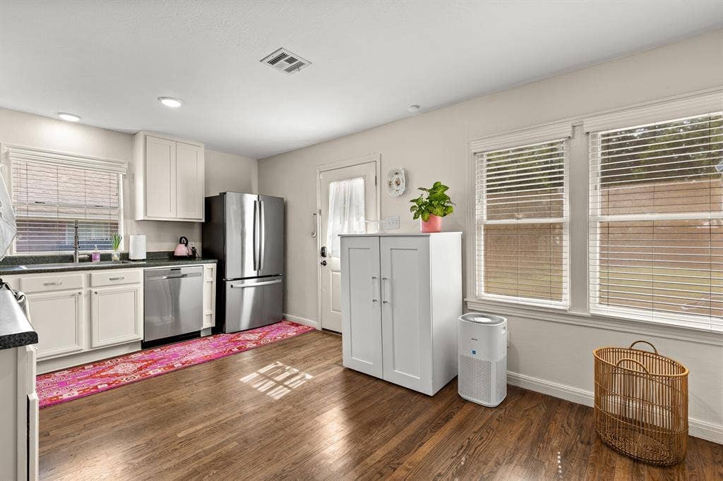 2425 S 2nd Street, Waco, TX 76706 Kitchen featuring stainless steel appliances, white cabinetry, dark stone-finish countertops, wood-finish flooring, and multiple windows